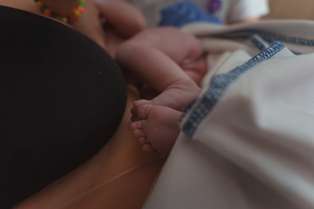Newborn feet resting on mother right after birth, hospital birth in Arnhem