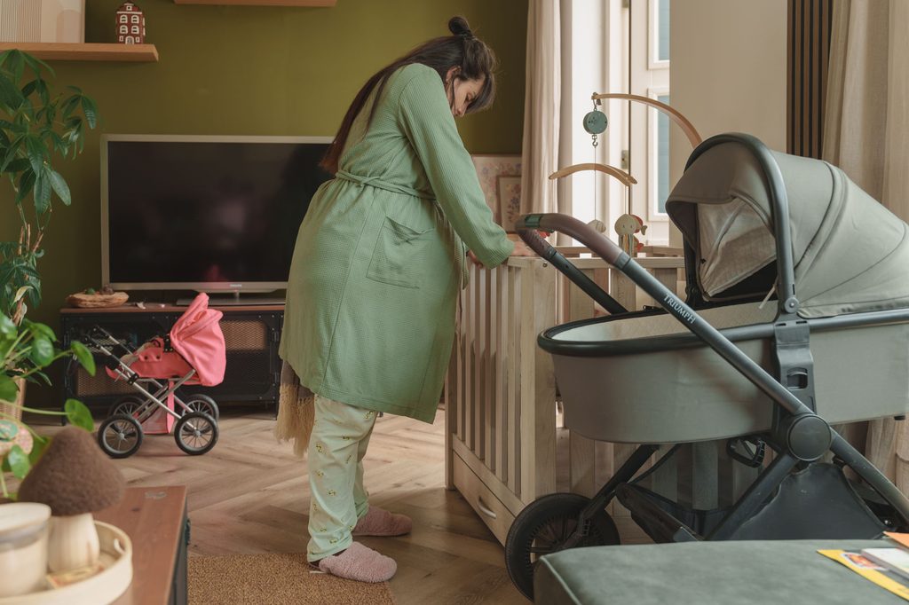 Pregnant mother at home next to the pram, ready for her second baby