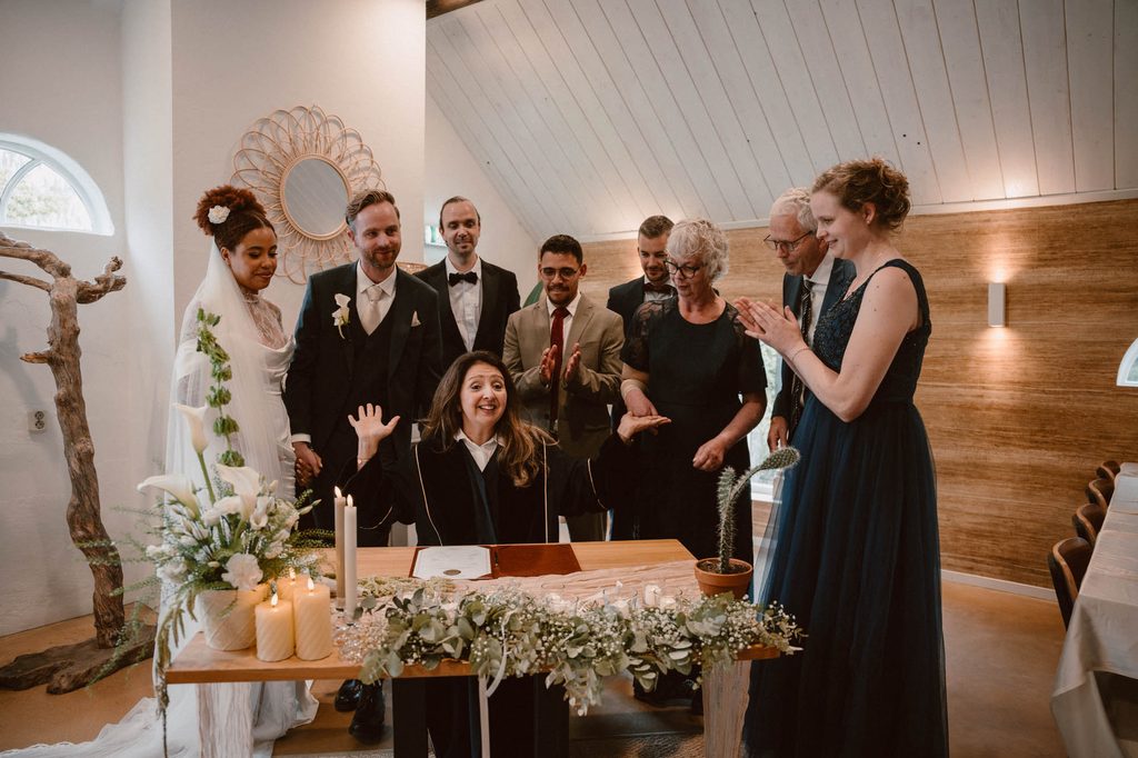 Couple signing at the ceremony surrounded by family, Mexican-Dutch wedding in the Netherlands