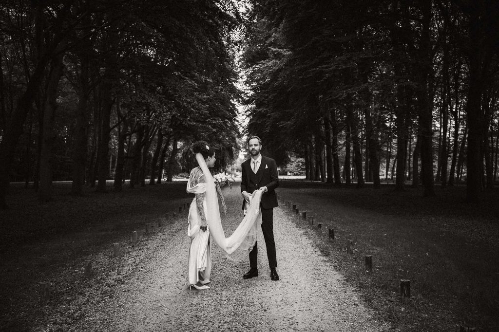 Bride and groom walking under the trees, black and white, Mexican-Dutch wedding in the Netherlands